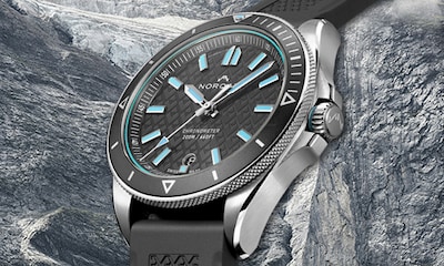 Norqain Adventure Collection. Image of grey and turquoise watch on icy stone background. Tap to Shop Adventure collection image