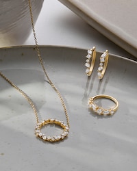Image of diamond and yellow gold necklace, earrings and ring on ceramic background - tap to shop all jewellery image