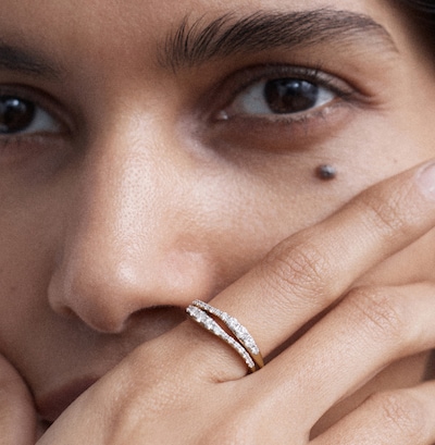 Image of a close-up of a hand wearing a Riva collection diamond-studded ring, partially covering the lower face. image
