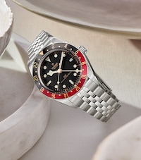 Image of tudor black bay on cream ceramic dish. tap to shop all watches image